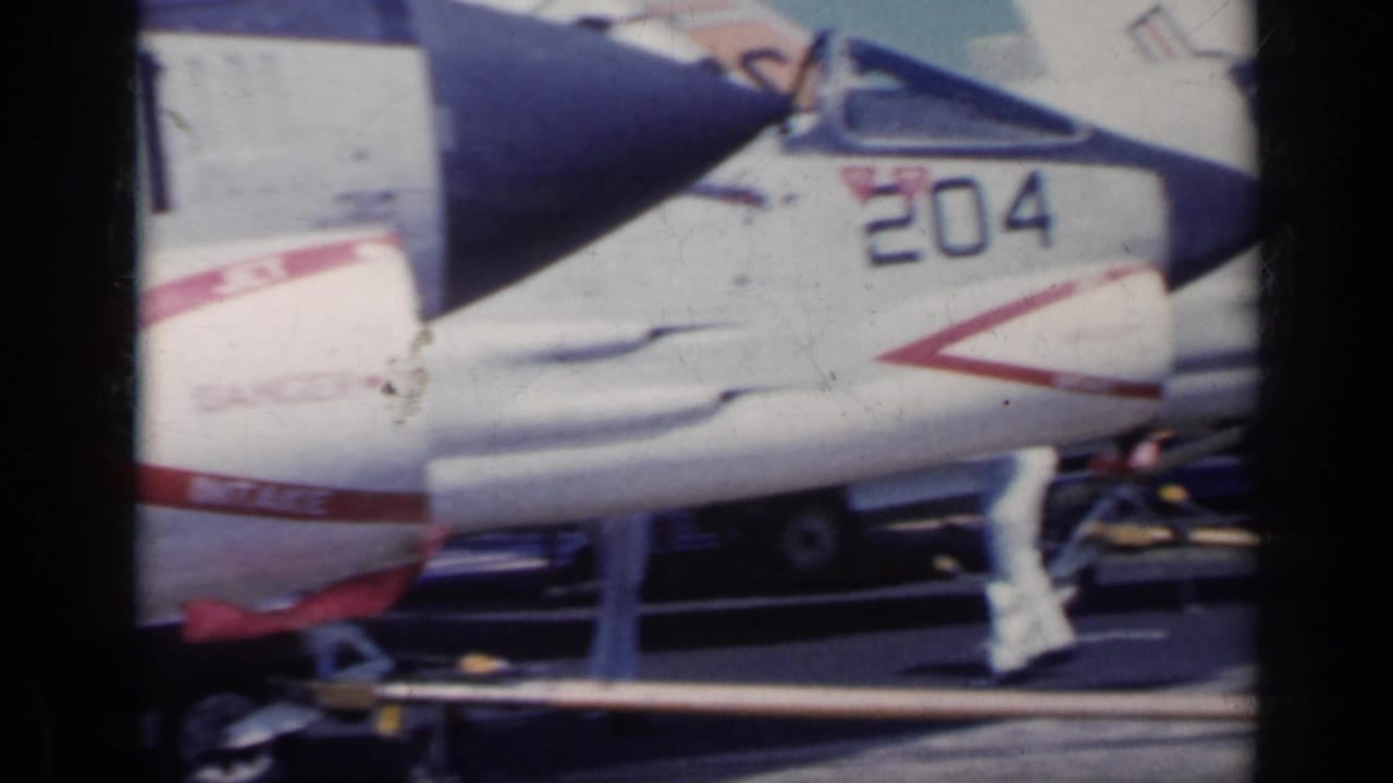 Close view of a white naval jet marked 204 on a carrier deck.
