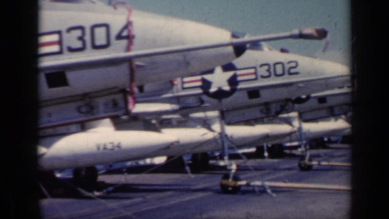 1962 carrier-deck view of white military jets with visible numbers 304 and 302, parked close together with deck gear below.