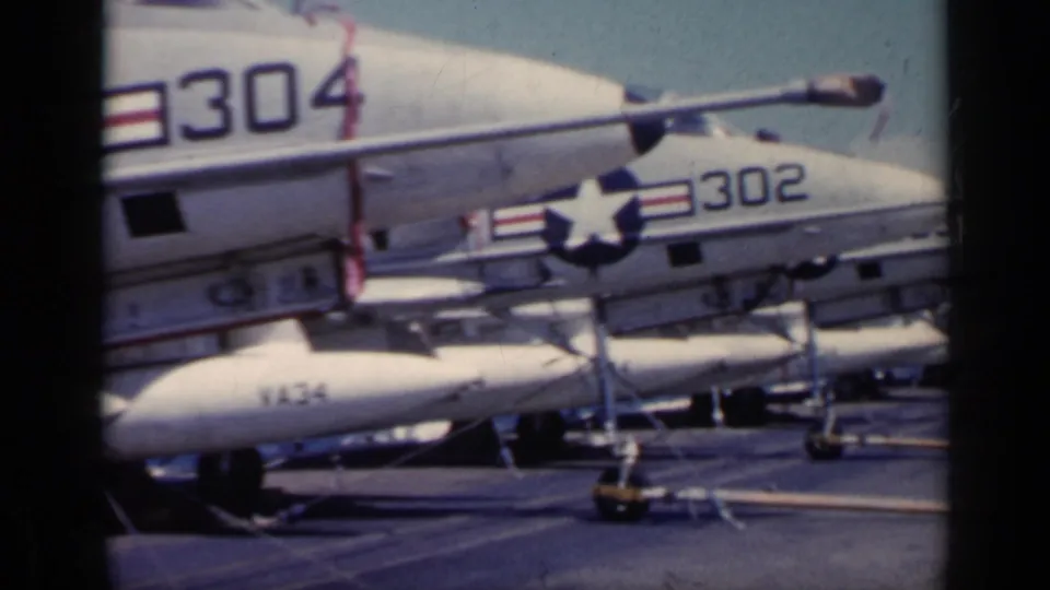 1962 carrier-deck view of white military jets with visible numbers 304 and 302, parked close together with deck gear below.