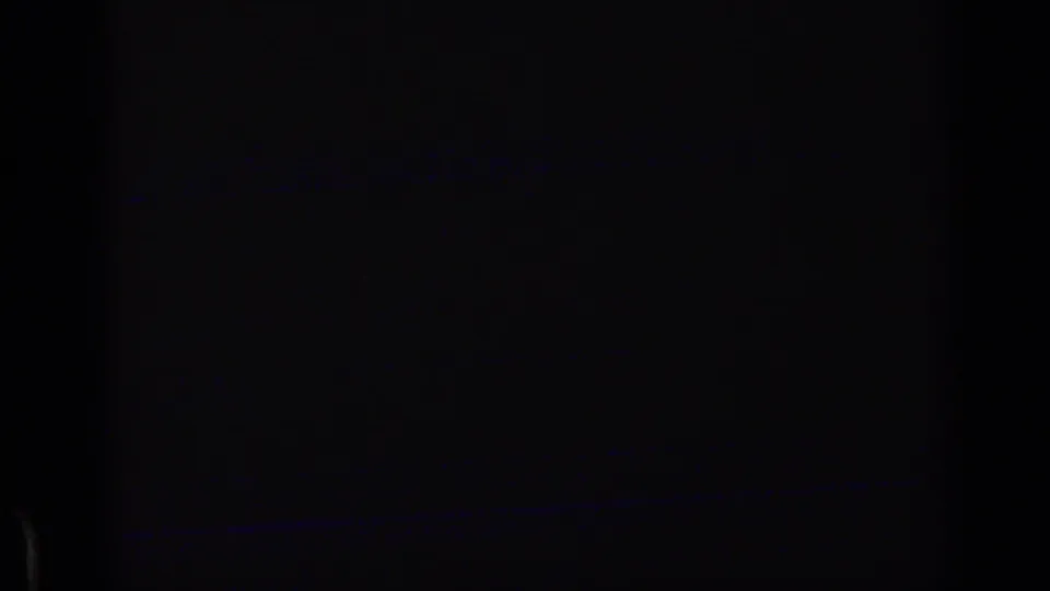 Underexposed or obstructed 8mm frame with a dark foreground and a faint horizontal blue band near the bottom.