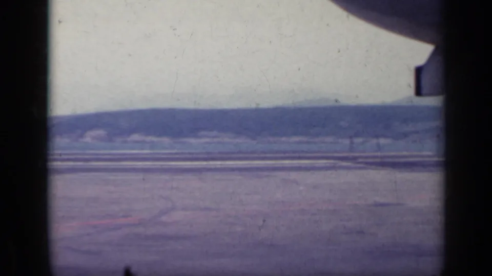1962 Italy travel frame showing a broad flat surface, distant hills, pale sky, and dark framing from the camera position.