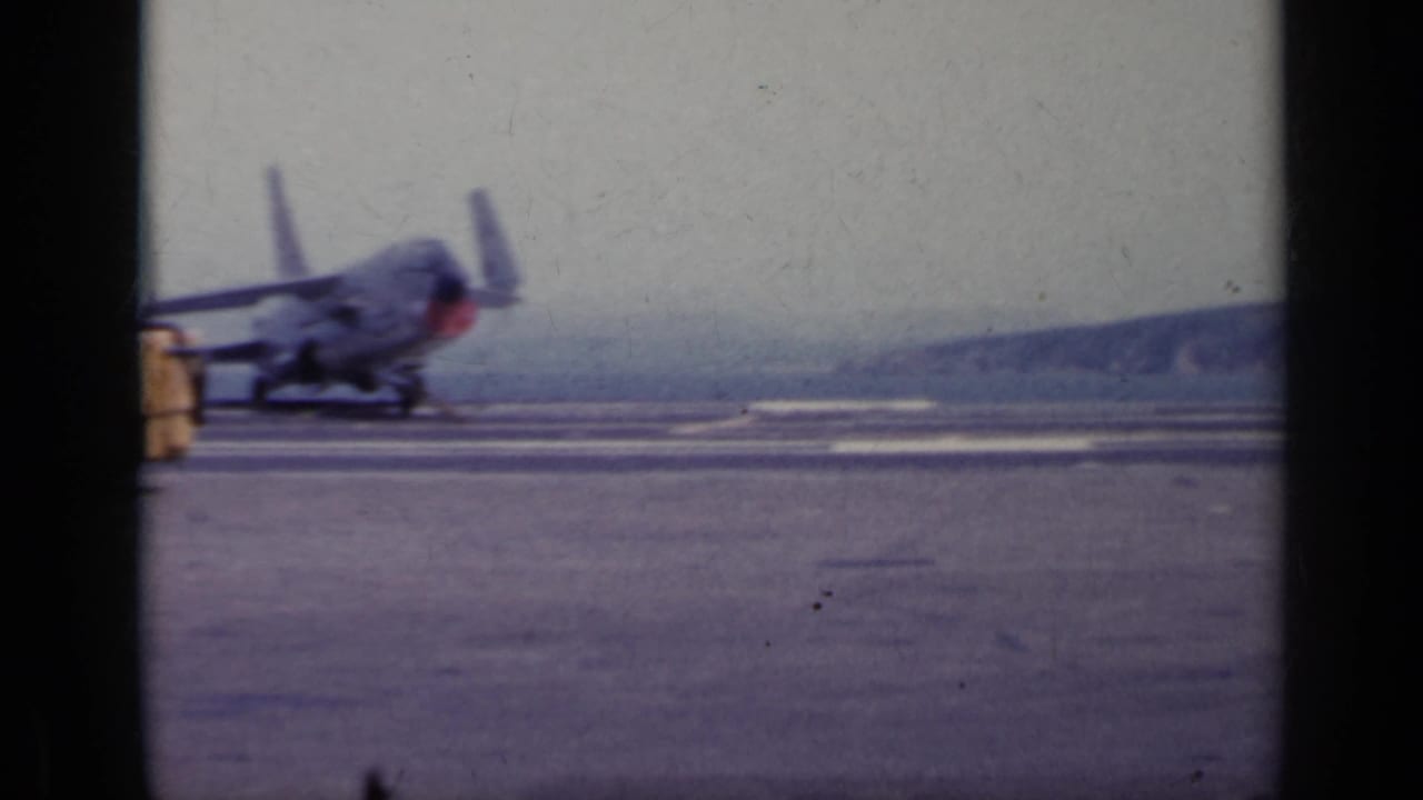 Propeller aircraft on a paved airfield with a yellow vehicle partly visible at the edge.
