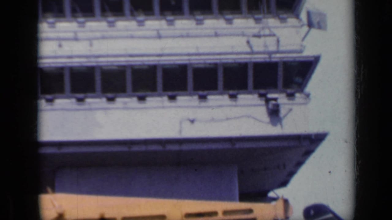 Close view of a white ship bridge with rows of windows and part of a yellow foreground structure.