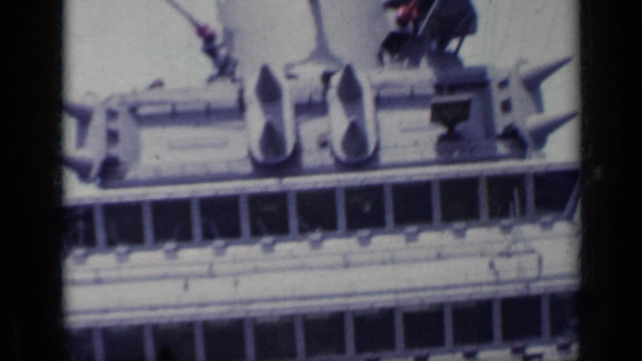 Close view of ship superstructure with railings and deck equipment framed by dark film borders.