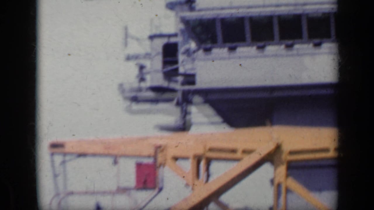 1962 Italy dockside frame with part of a cruise ship, a yellow pier crane and pale sea in the background.
