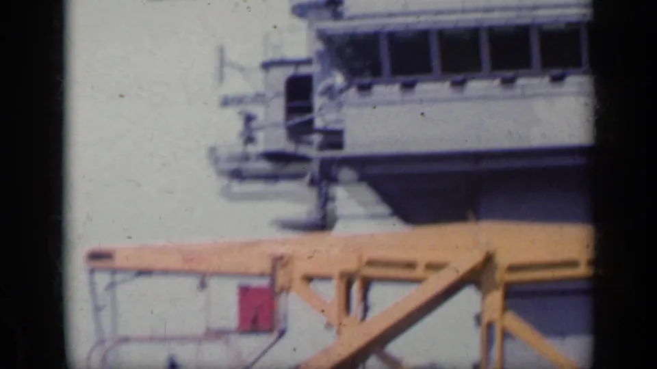 1962 Italy dockside frame with part of a cruise ship, a yellow pier crane and pale sea in the background.