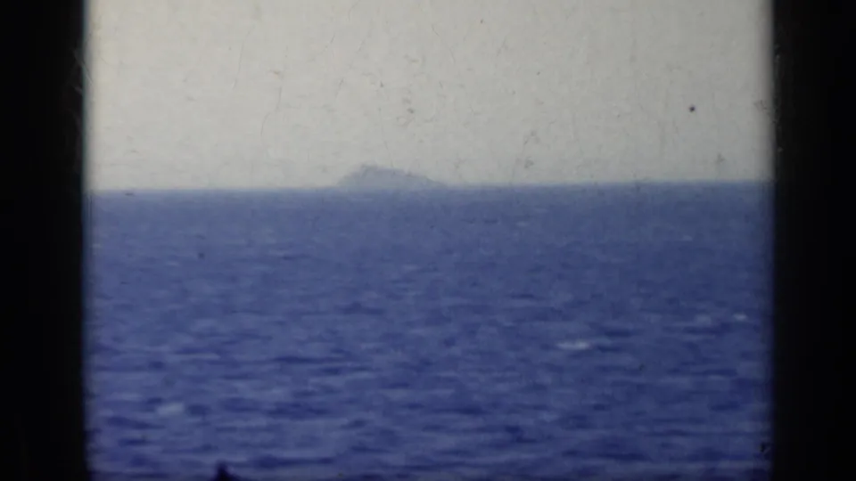 1962 Italy 8mm frame showing open sea, a faint distant island or mountain, and soft haze.