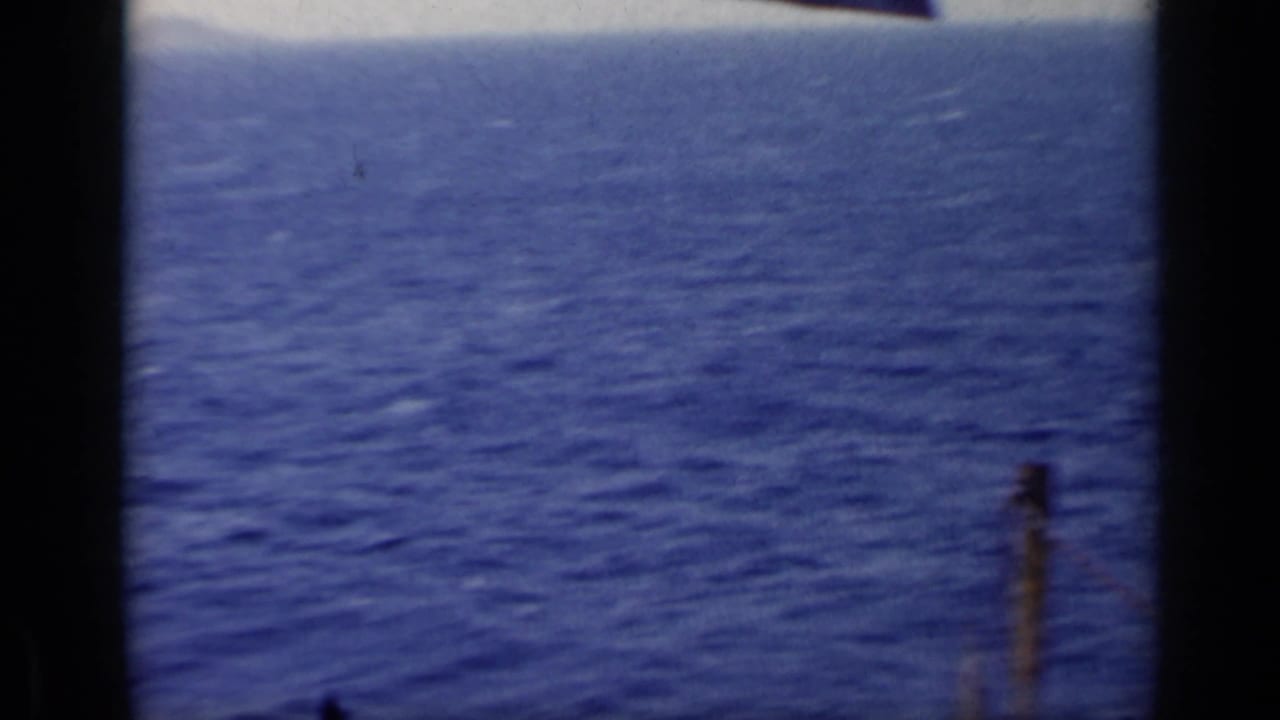 Open blue sea with horizon and partial boat structure at right.