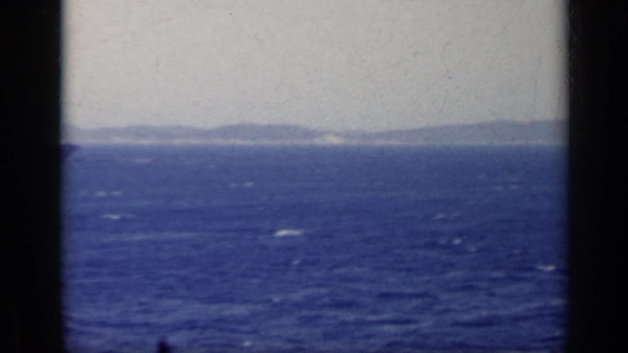 Blue sea with hazy mountains on the horizon, framed by dark vertical edges.