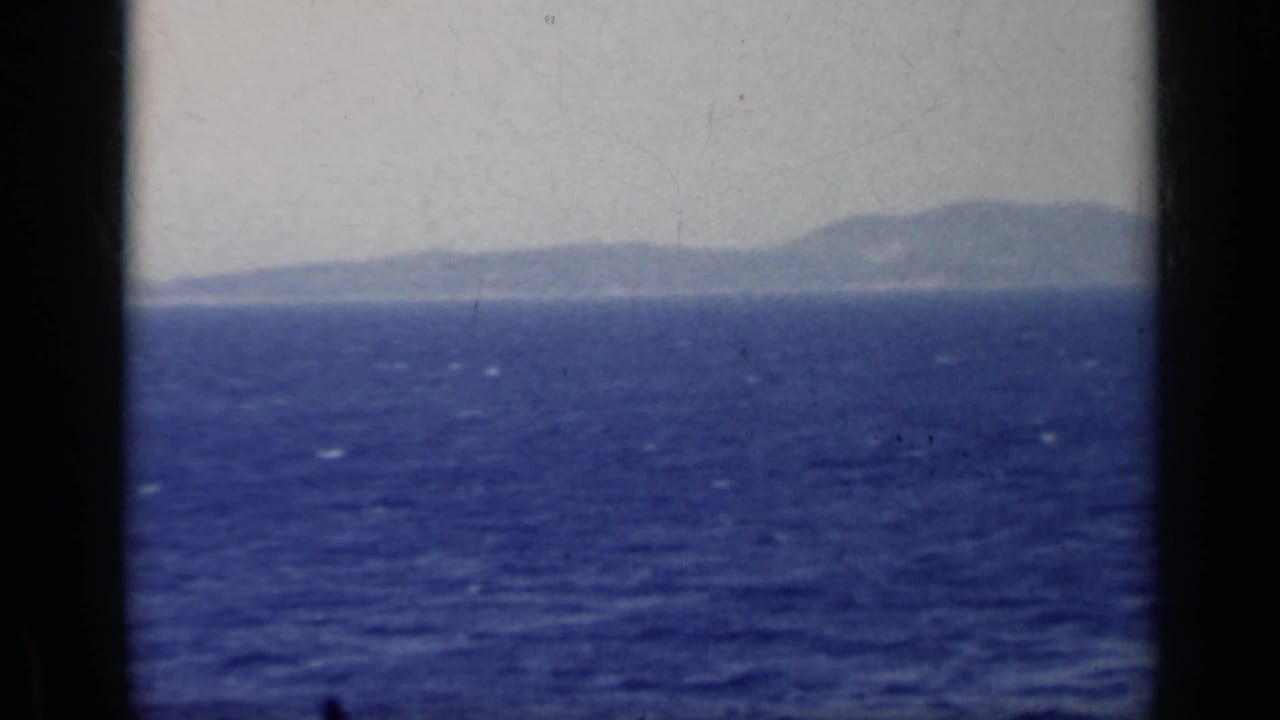 Open water and distant landforms under a pale sky, divided by dark frame edges.