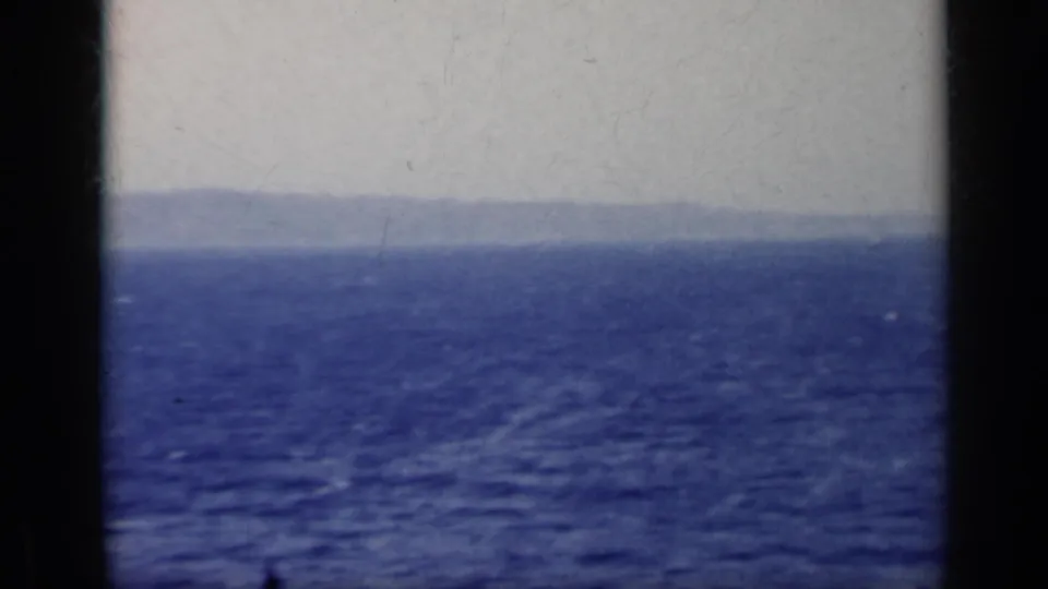 1962 Italy 8mm seascape with rippled blue water and a faint mountainous horizon, viewed from a vessel.