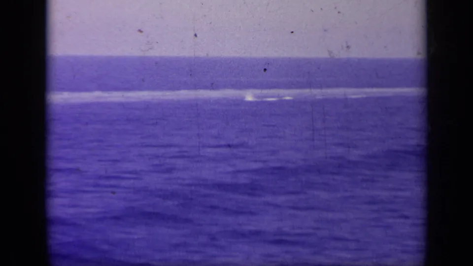 1963 8mm sea view from the carrier, emphasizing blue water, distant horizon, and the physical film frame edges.