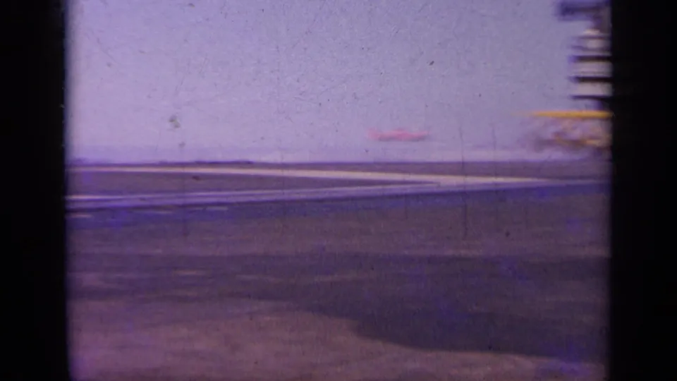 1963 Greece 8mm frame showing a broad carrier-deck surface with runway-like markings and a low horizon.