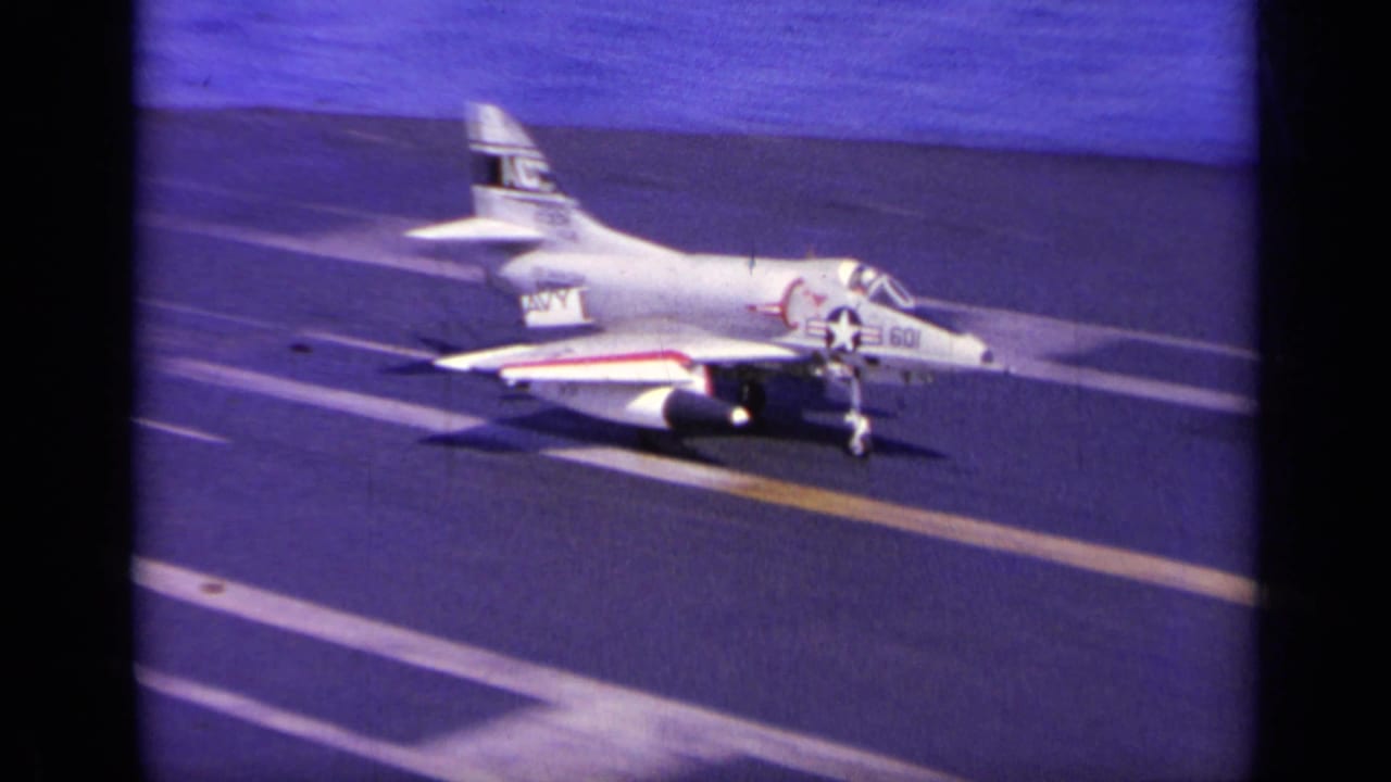 White U.S. Navy jet on a carrier deck with star insignia and tail markings.