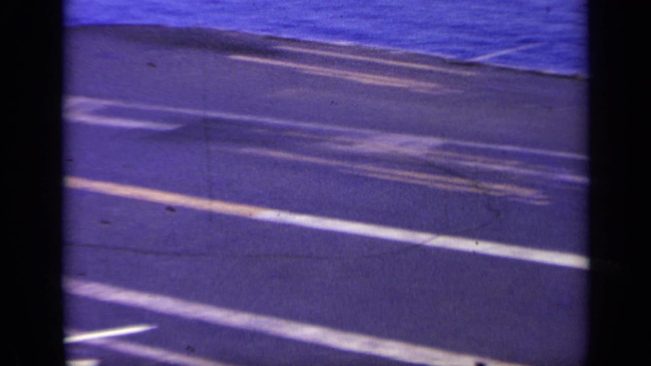 Aircraft carrier deck markings and blue sea during a camera pan.