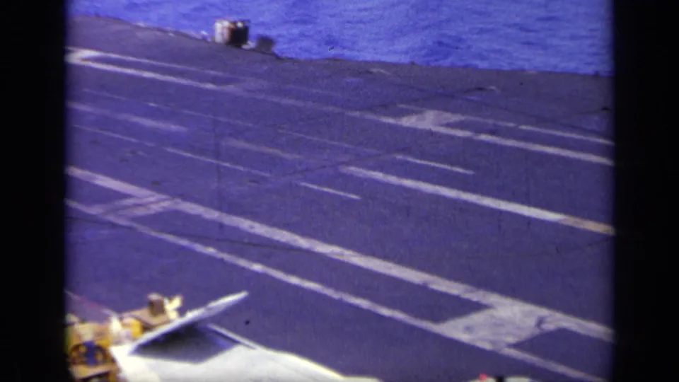 1963 Greece carrier-deck view with part of a jet wing in the foreground and open sea beyond the deck.