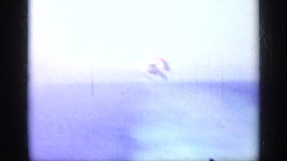 The jet is barely visible through bright exposure flare as it leaves the carrier deck during the takeoff sequence.