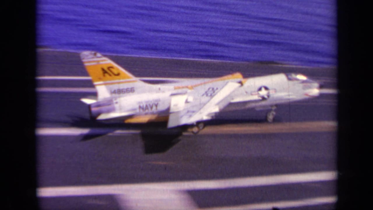 U.S. Navy jet rolls along the carrier deck with a yellow tail fin.