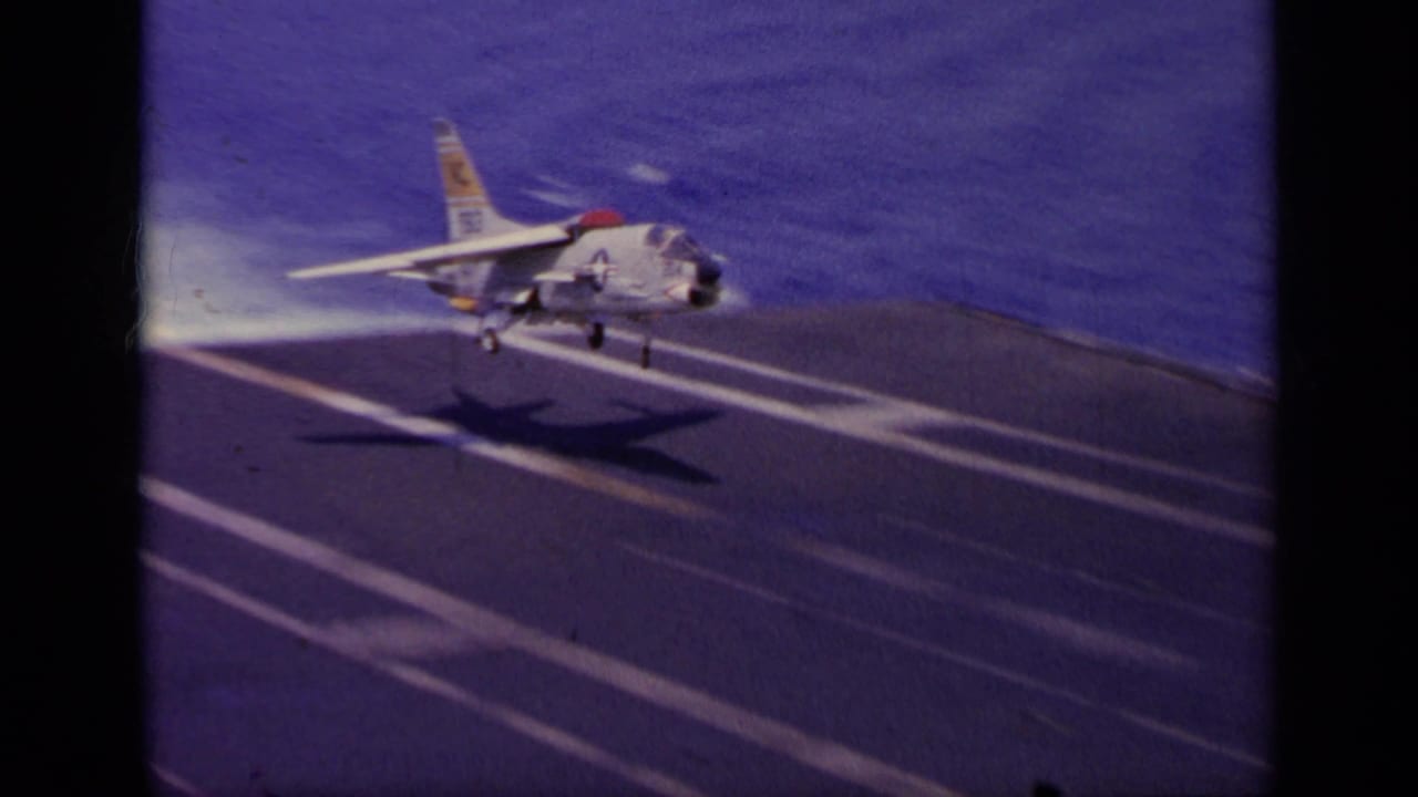 U.S. Navy jet touching down on an aircraft carrier deck at sea.