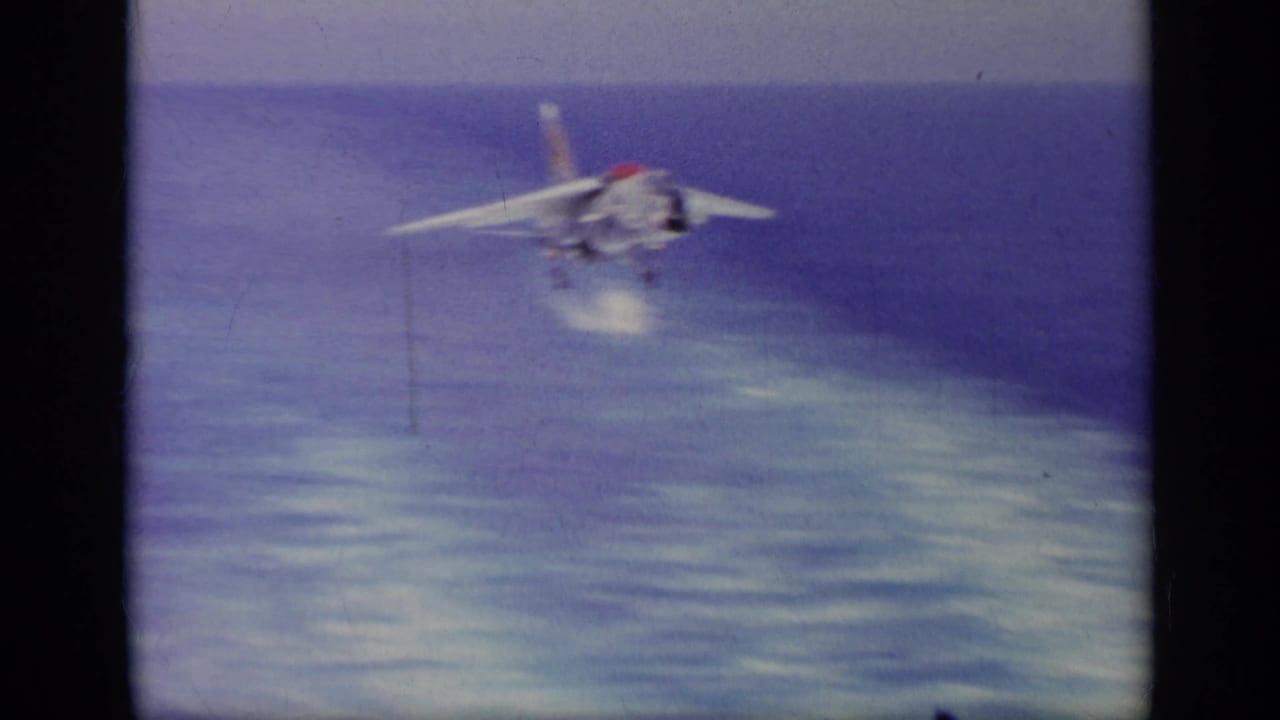 Jet approaching over open water with landing gear down.
