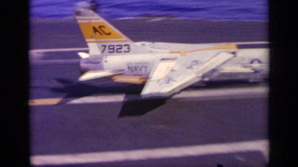 Close 1963 carrier-deck view of a U.S. Navy jet showing tail number 7923 or similar markings and the wing over deck lines.