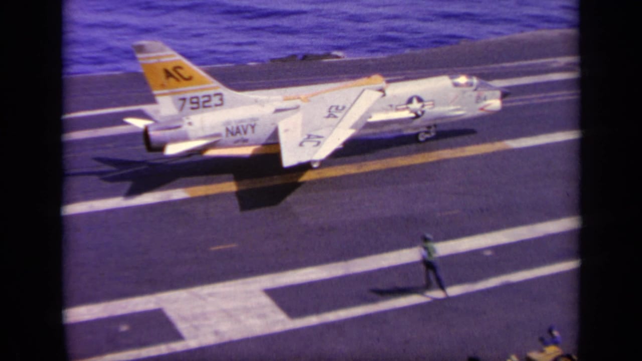 1963 Greece-associated 8mm frame showing a white U.S. Navy jet marked 7923 on a carrier deck, with deck crew and blue sea beyond.