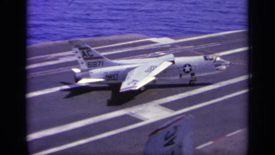 1963 Greece home-movie frame of a U.S. Navy jet marked AC 6871 positioned near carrier deck lines before launch.