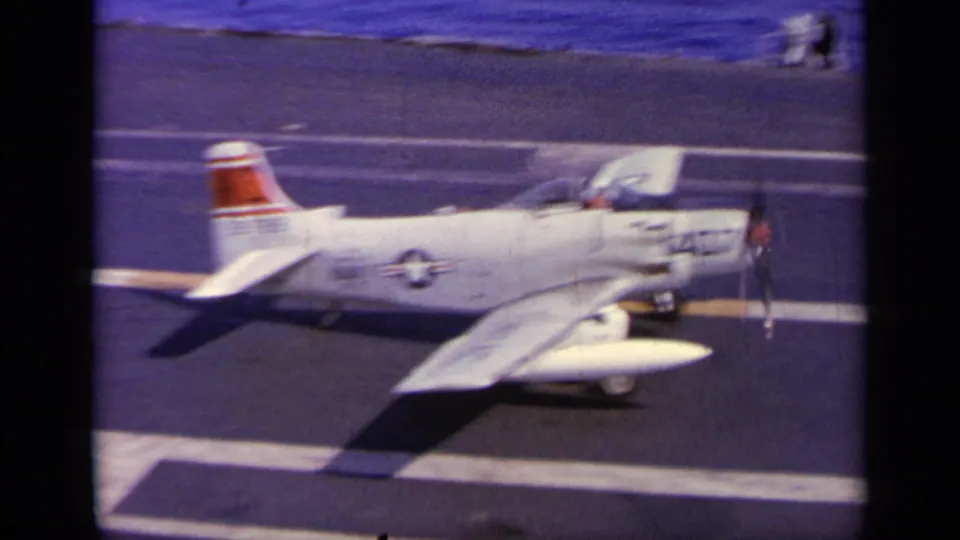 A side view shows aircraft 407 continuing across the carrier deck, with red tail markings, cockpit canopy, and deck crew in the distance.