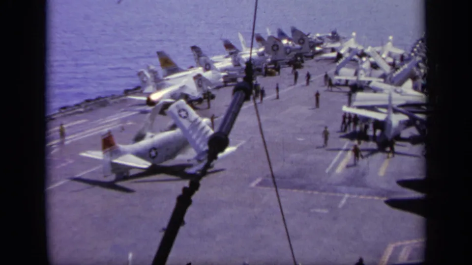 The wider 1963 Greece view shows multiple Navy aircraft parked on the carrier deck with crew moving between them.
