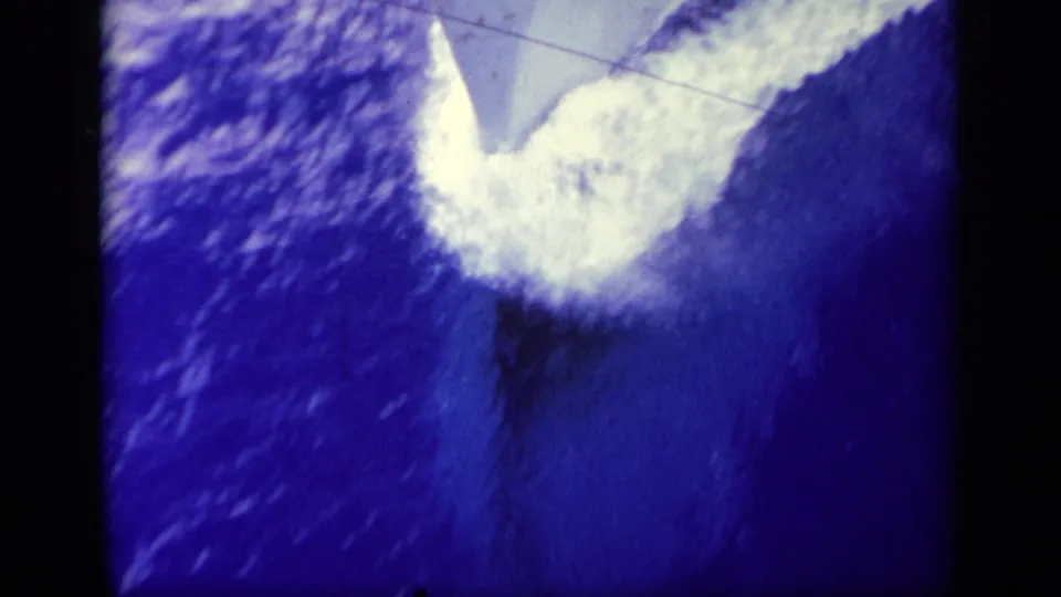 Final 8mm frame shows deep blue water and a bright wake or disturbed sea surface, likely viewed from the ship or aircraft.