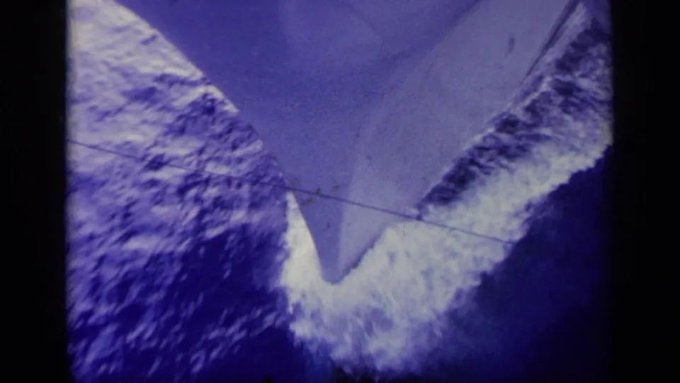 1963 Greece 8mm frame with the bow seen from above as water churns white along the vessel.