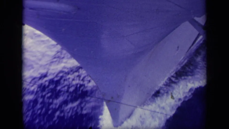 1963 Greece 8mm frame showing the ship’s bow and deck edge over blue water with a foamy trail.
