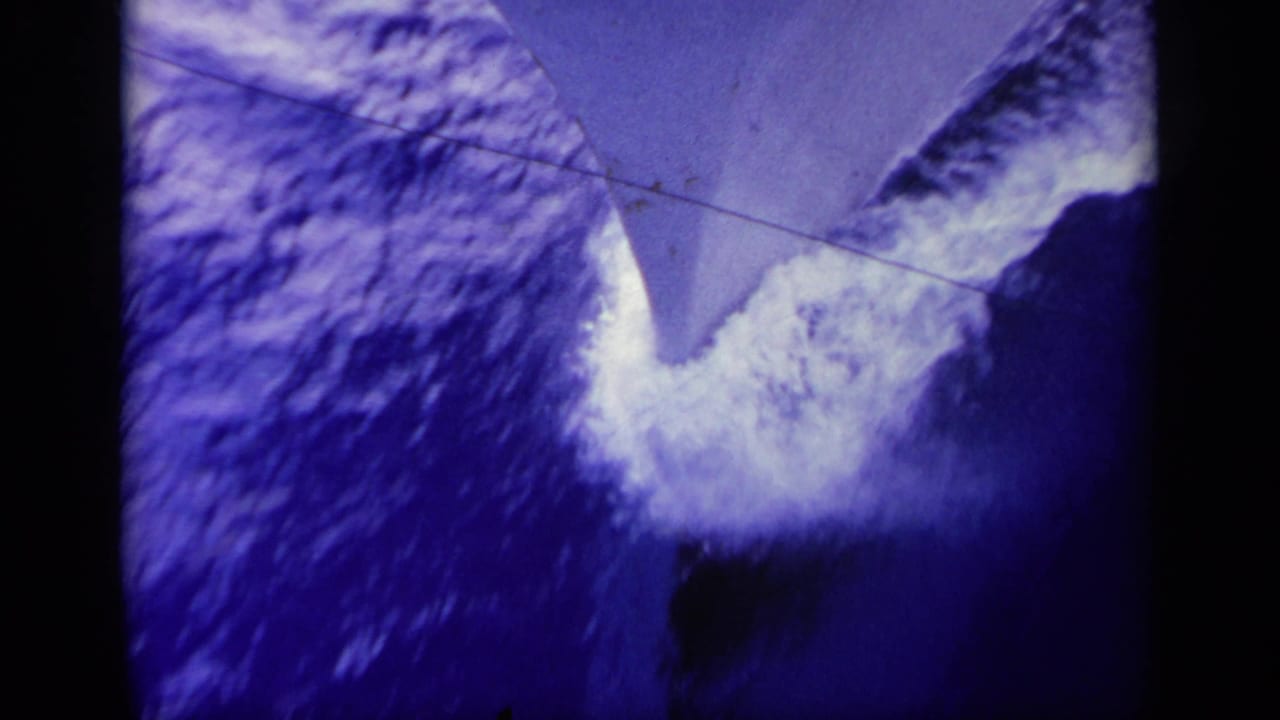 Close view of white wake curling around a boat bow in dark blue water.