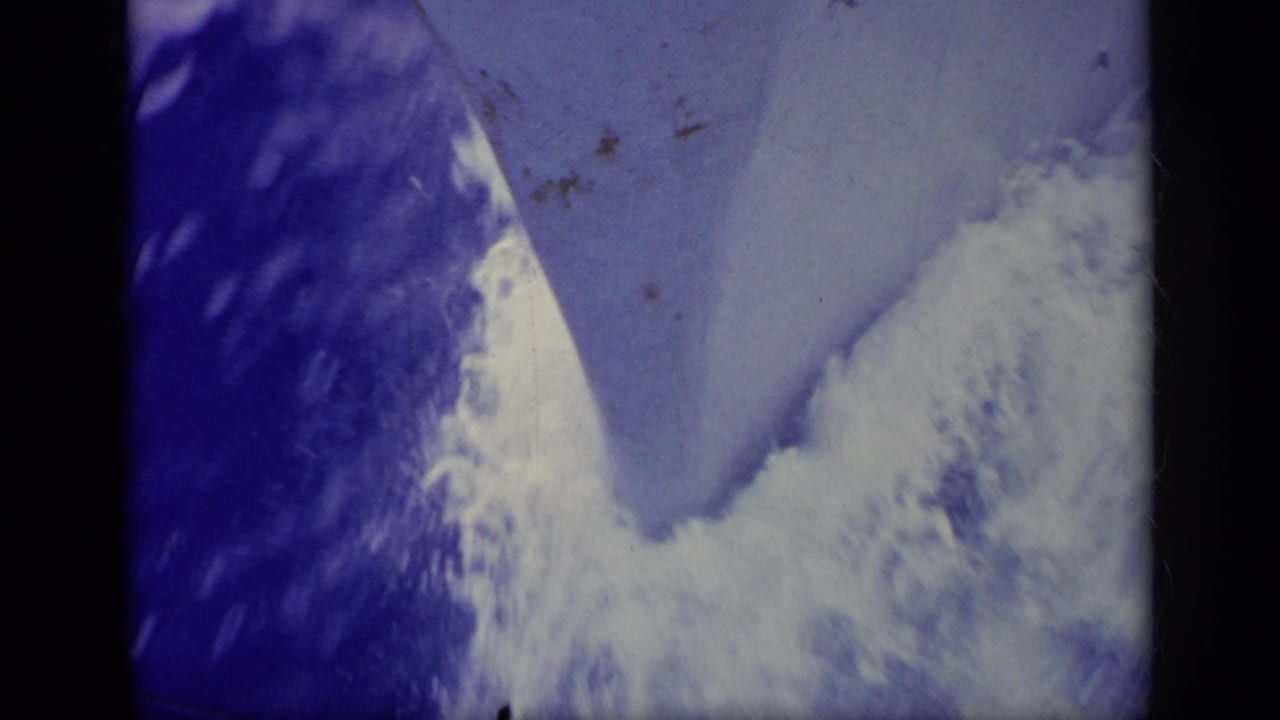 1963 Greece 8mm frame showing blue-tinted sea or wake texture with dust, grain, and dark film gate edges.