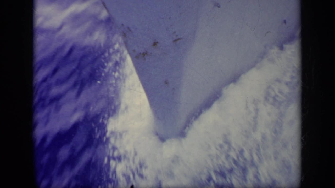 Blue-tinted water or wake pattern with film dust and dark vertical border.