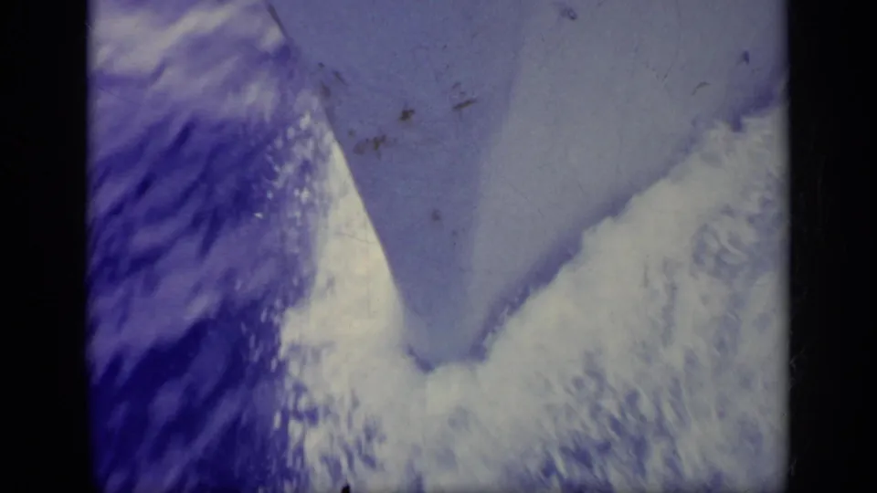 1963 Greece home-movie frame with blue sea or wake patterns, visible grain, dust, and dark film-edge framing.