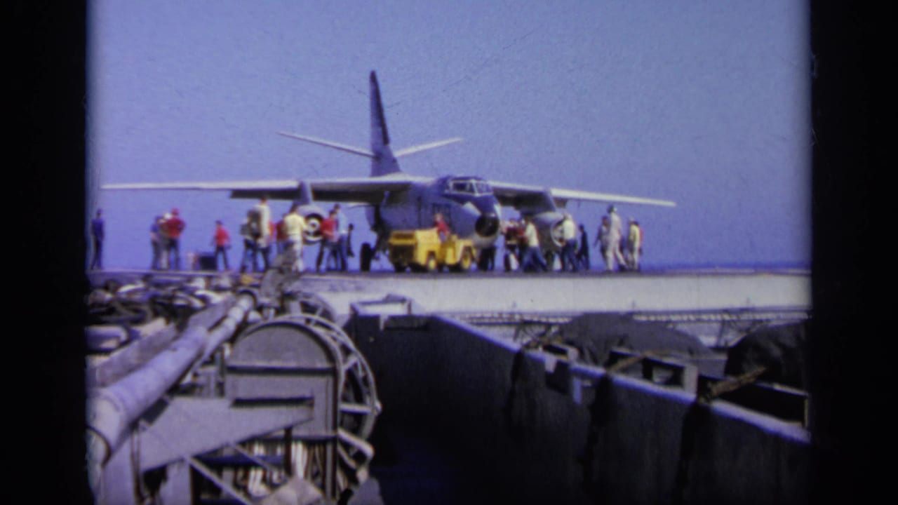 1963 Greece 8mm frame showing a military aircraft on a carrier deck, with personnel around the nose and sea in the background.