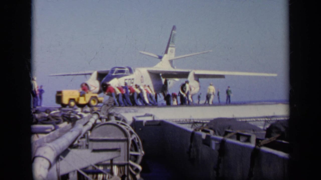 1963 Greece 8mm frame showing a U.S. Navy jet marked 509 being handled by crew on an aircraft carrier deck.
