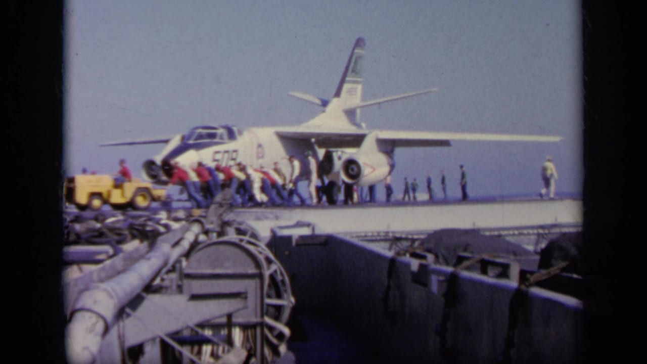 1963 Greece 8mm frame showing the jet marked 509 on a carrier deck as crew members prepare or move around it.