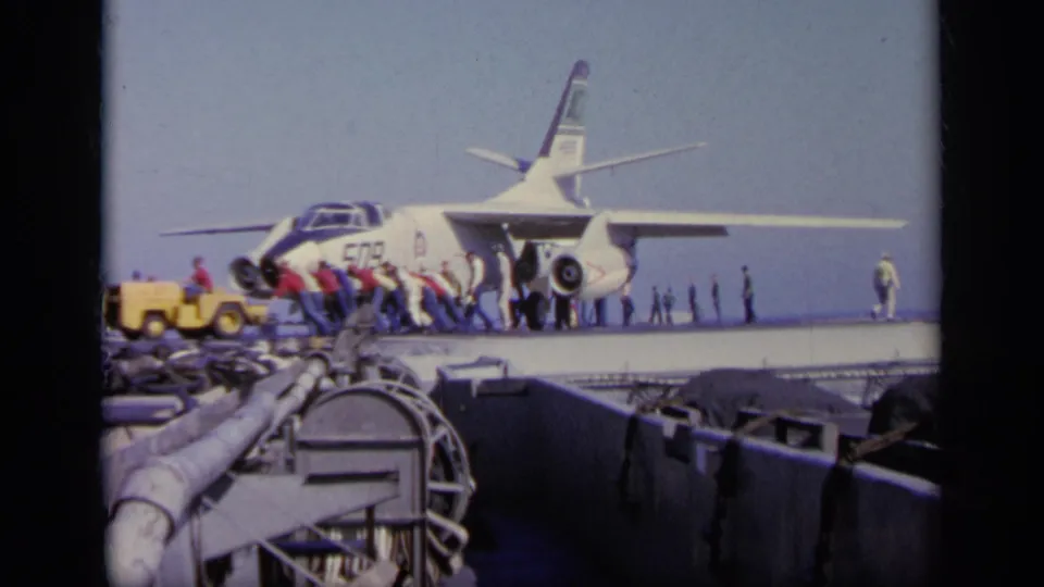 1963 Greece 8mm frame showing the jet marked 509 on a carrier deck as crew members prepare or move around it.