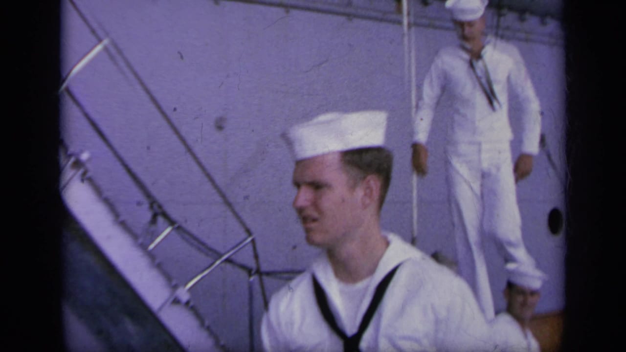 Sailors in white uniforms are seen beside carrier deck stairs and railings, with ship surfaces filling the background.