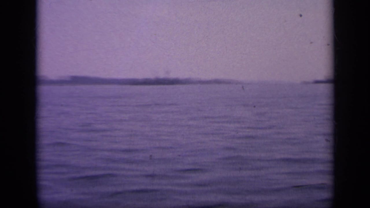 Calm sea with a hazy horizon and distant low landforms.