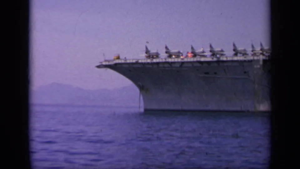 1963 Greece 8mm frame showing the bow of an aircraft carrier with multiple aircraft lined along the deck.