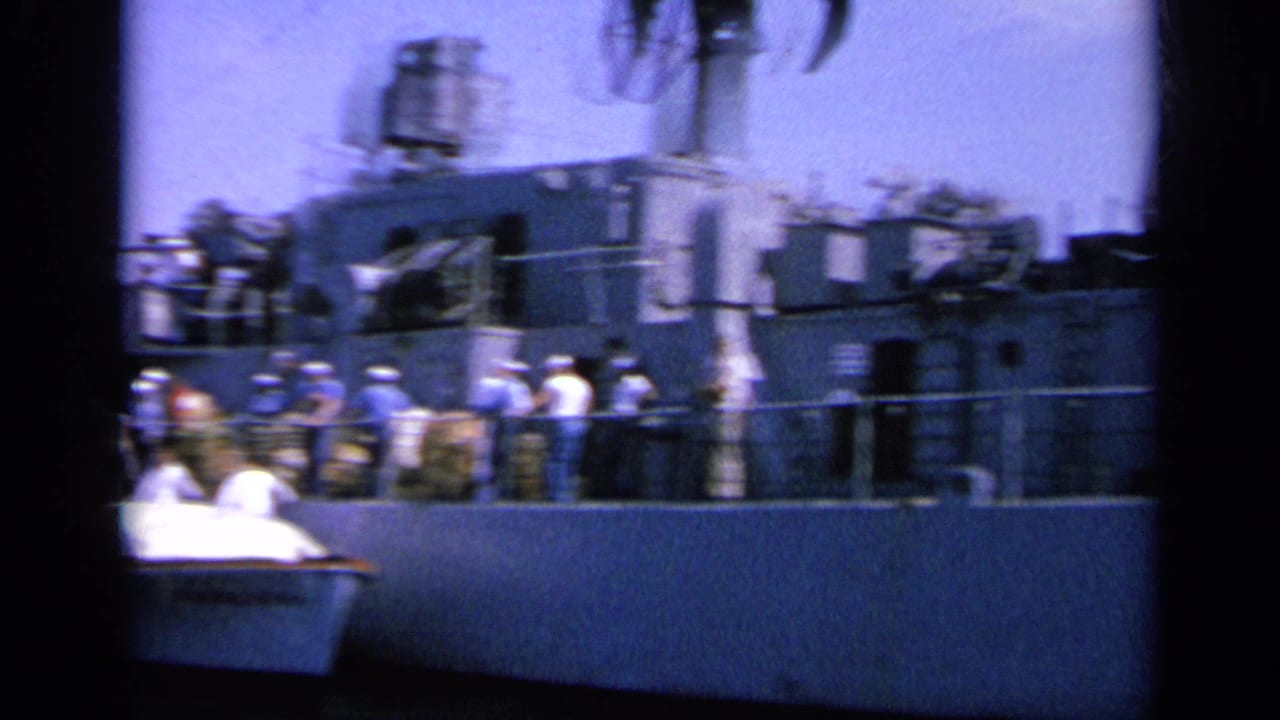 Closer view of sailors along the side of a gray naval vessel with equipment above deck.