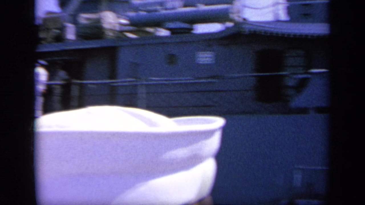 1963 Greece 8mm frame with a white sailor cap in the foreground and a gray naval ship side behind it.