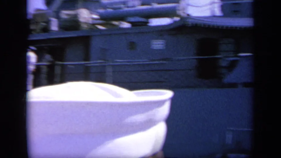 1963 Greece 8mm frame with a white sailor cap in the foreground and a gray naval ship side behind it.