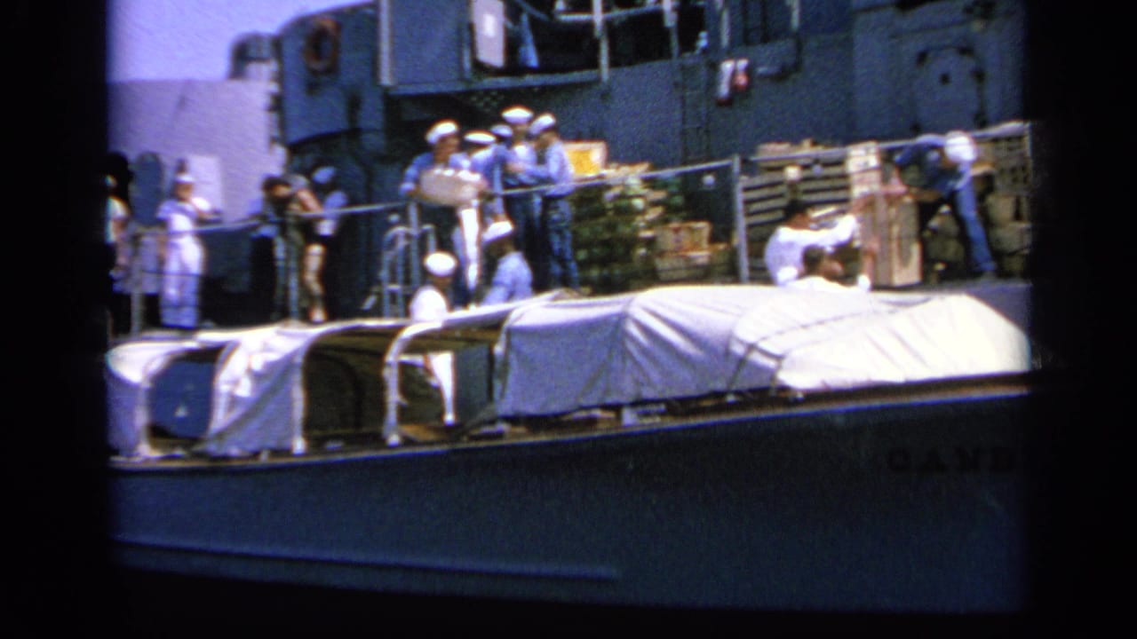 1963 Greece 8mm frame with sailors in blue and white uniforms gathered by supplies on a naval ship deck.