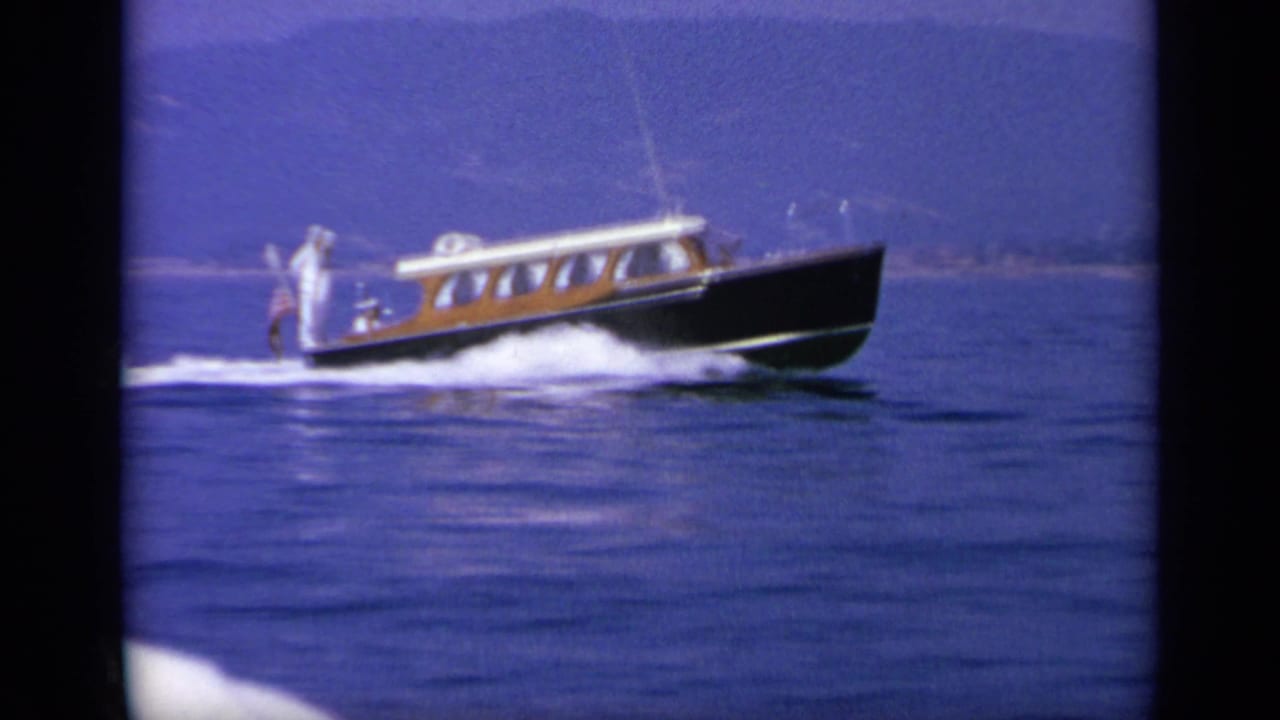 1963 Greece 8mm frame showing a small motorboat moving across open water near a distant shoreline.