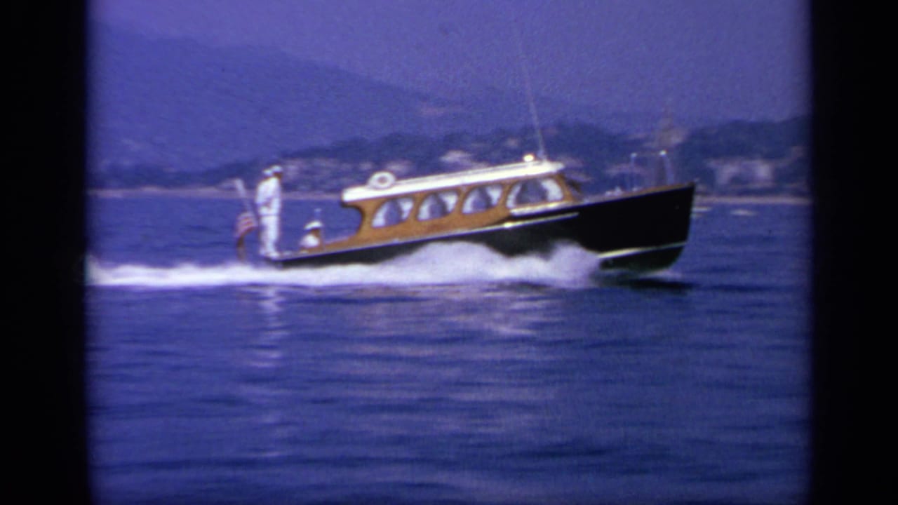 Speedboat continues across calm water with shoreline and hills in the background.