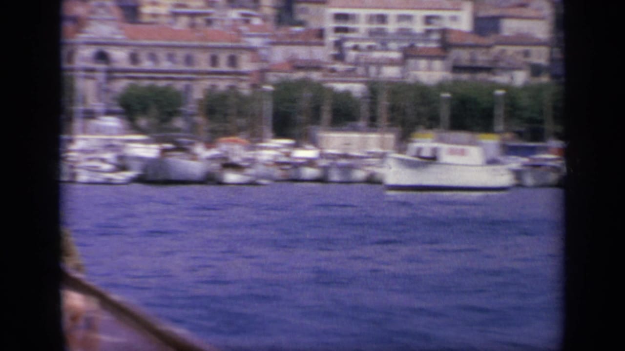 Harbor water with small boats and waterfront buildings behind dark foreground framing.